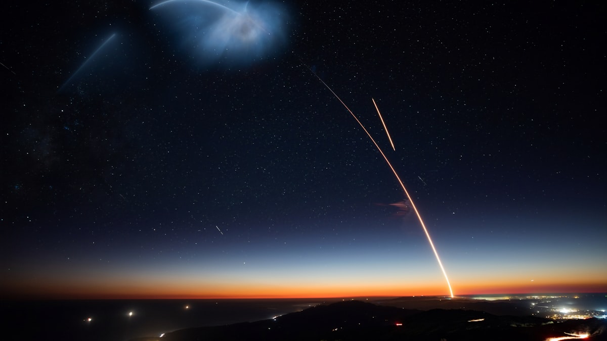 Long exposure photography of a rocket launch arcing into the night sky
